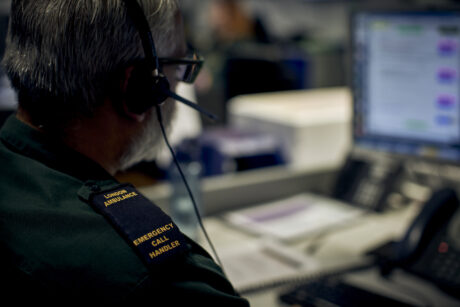 A call handler with a headset and their epaulettes which read London Ambulance Emergency Call Handler