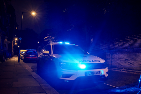 An ambulance car with flashing blue lights parked on a street at night