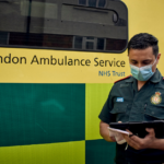 A medic stood in front of an ambulance using an iPad