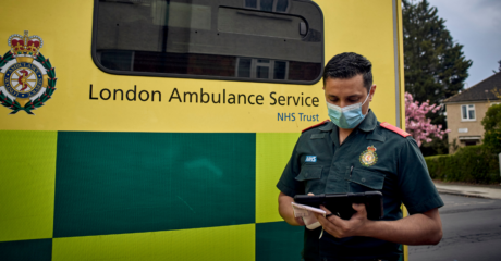 A medic stood in front of an ambulance using an iPad
