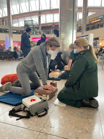 A medic watches as a person performs chest compressions on a dummy