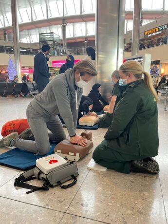 A medic watches as a person performs chest compressions on a dummy