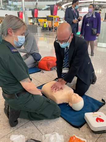 A medic watches as a person performs chest compressions on a dummy