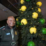 John standing smiling next to the Christmas tree