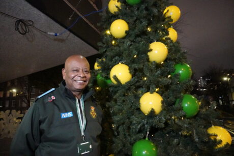 John standing smiling next to the Christmas tree