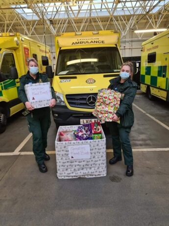 Two LAS medics with boxes of donated items in an ambulance station