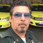 Brett photographed in uniform with two ambulance cars behind him