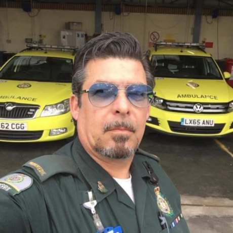 Brett photographed in uniform with two ambulance cars behind him