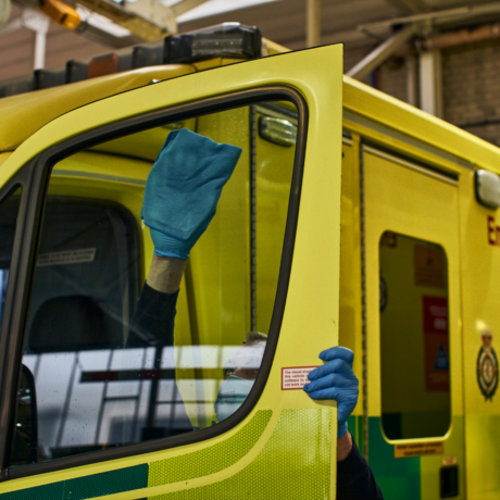 A Make Ready staff member cleaning the inside of the window on an ambulance front door