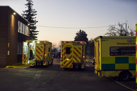 A group of ambulances parked in an ambulance station at dusk