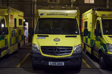 An ambulance parked inside an ambulance station with other ambulances either side