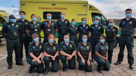 A group of newly qualified paramedics posing for a group photograph in front of an LAS ambulance