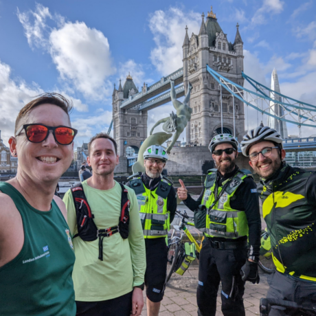 The runners and their cycle paramedic chaperones take a selfie in front of Tower Bridge