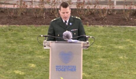 LAS Clinical Team Manager, Jason Morris, in ceremonial uniform, speaks at a podium during the event