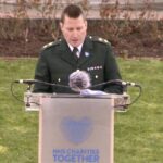 LAS Clinical Team Manager, Jason Morris, in ceremonial uniform, speaks at a podium during the event