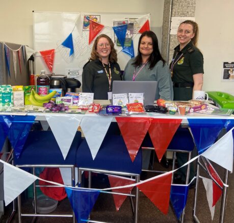 Wellbeing desk with Jubilee decorations in the photo Co-ordinator Lucy (centre) with Emergency Call Co-ordinators Charis and Lucy