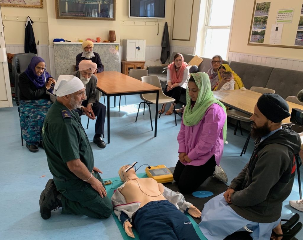 A picture of Ron Dhesi sharing CPR skills with members of the Woolwich Gurdwara