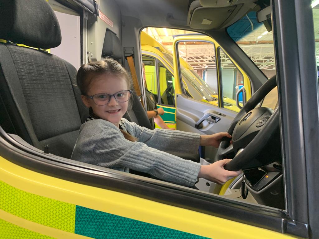 A picture of Cali-Maii in a London Ambulance vehicle pretending to drive it. 