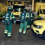 A picture of three HART paramedics in special protective uniforms, with lots of ambulance vehicles visible in the background.