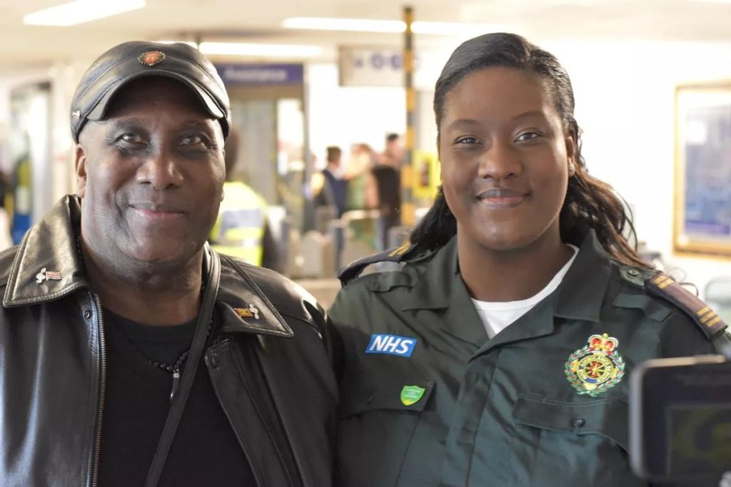 Image shows Eddie and Estelle in her LAS uniform at a Defibrillator campaign launch event in a tube station.