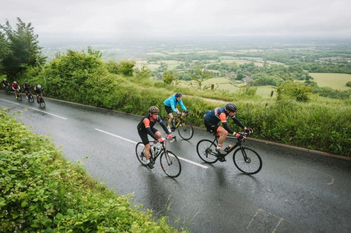 Image shows a group of cyclists cycling through the English countryside.