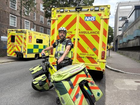 Cycle paramedic standing in front of ambulance
